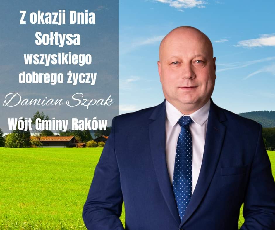 Wójt Gminy Raków - Damian Szpak na tle zielonej trawy, zabudowań i niebieskiego nieba