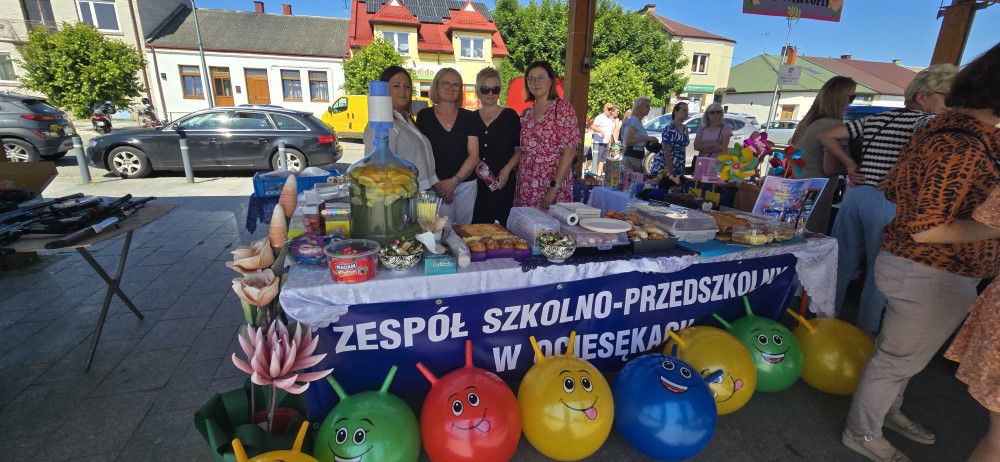 grupa ludzi stojących za stołem, przed stołem wielokolorowe dekoracje