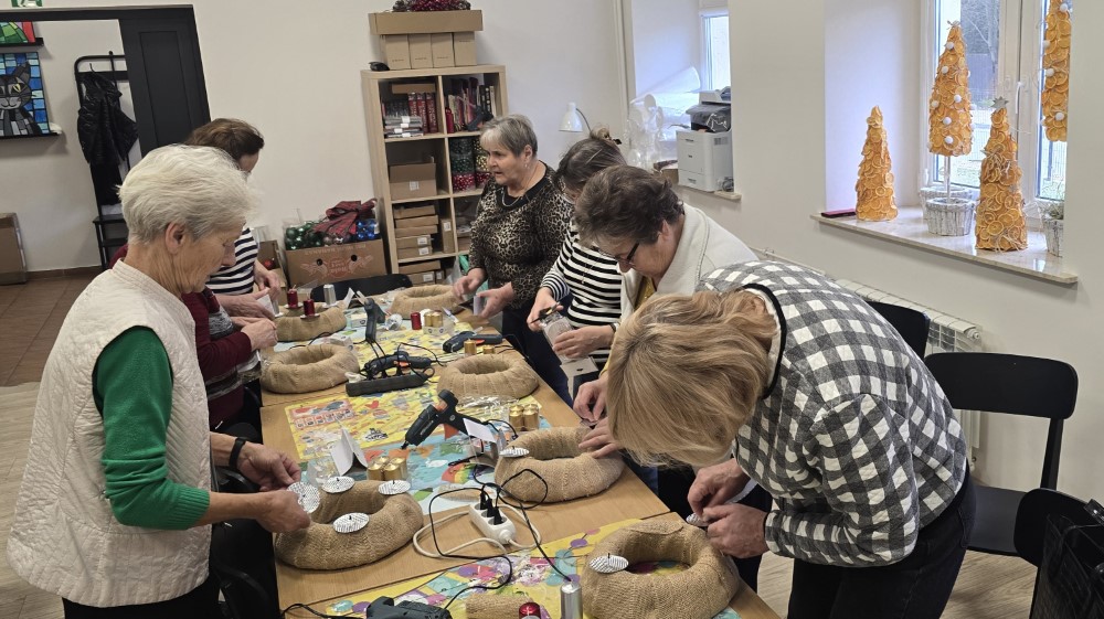 Zdjęcie przedstawia seniorów wykonujących wianki bożonarodzeniowe