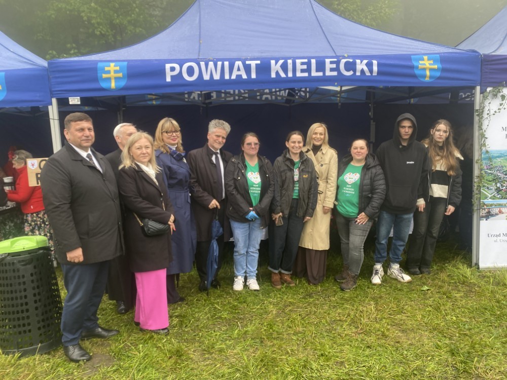 Osoby - kobiety i mężczyźni na tle granatowego namiotu z napisem "POWIAT KIELECKI"